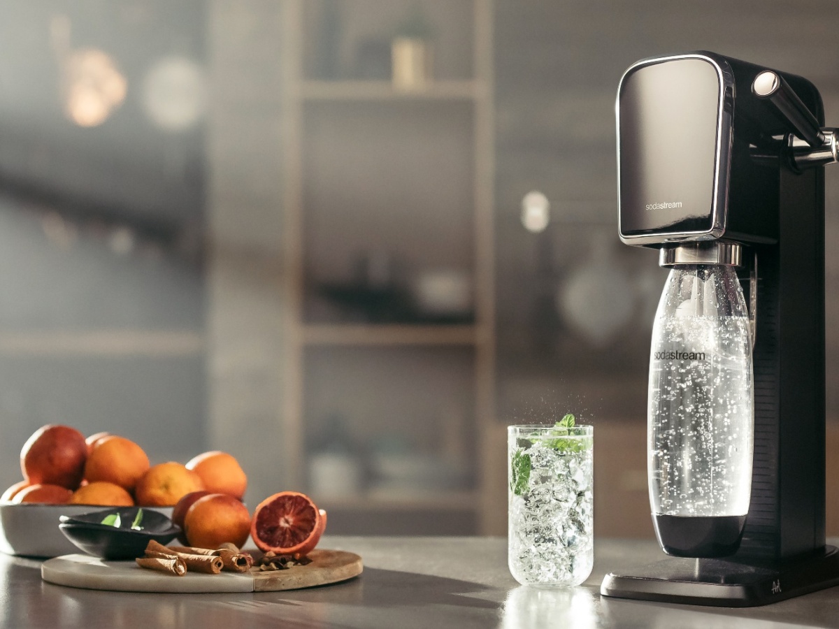 The SodaStream Art on a kitchen table with a glass of fizzy water